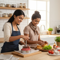 Two women using a stainless steel burger patty press in a kitchen